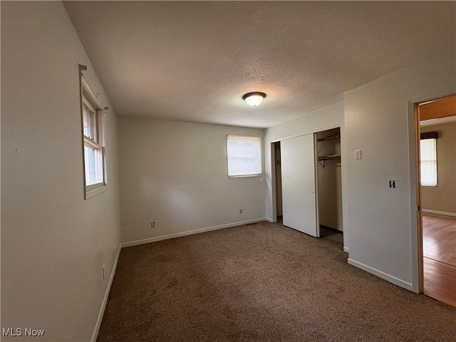 unfurnished bedroom featuring a closet, a textured ceiling, baseboards, and carpet floors