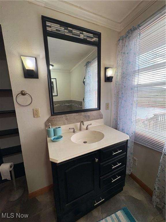 bathroom with baseboards, ornamental molding, and vanity