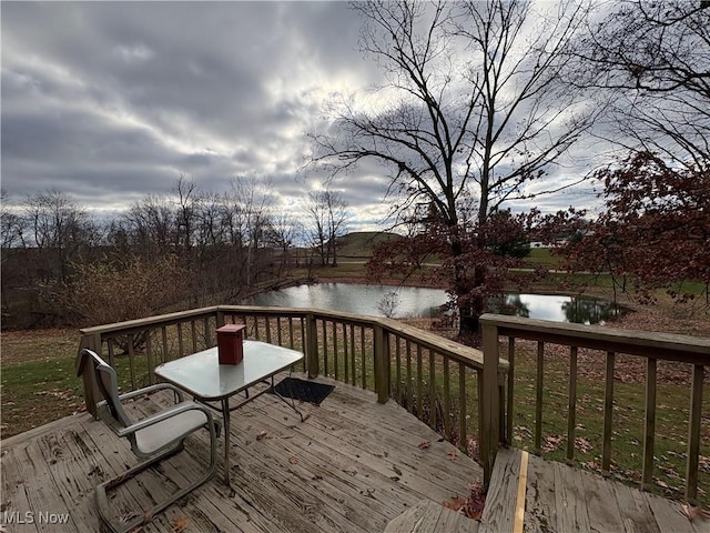 deck with a water view and outdoor dining space