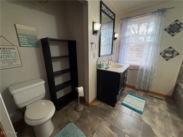 bathroom featuring vanity, toilet, baseboards, and ornamental molding