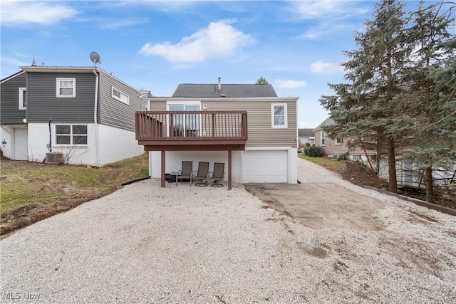 back of property with a garage, a deck, and central air condition unit