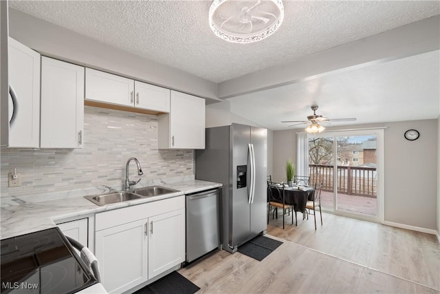 kitchen with stainless steel appliances, white cabinetry, sink, and light hardwood / wood-style flooring