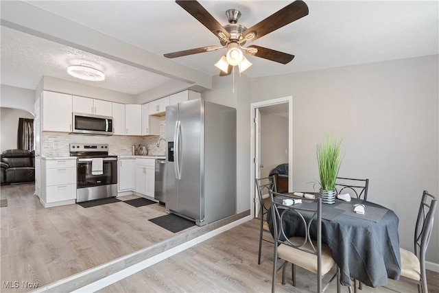 kitchen with white cabinetry, a textured ceiling, light hardwood / wood-style flooring, appliances with stainless steel finishes, and decorative backsplash