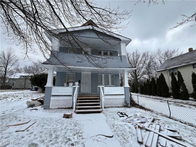 snow covered back of property featuring a porch