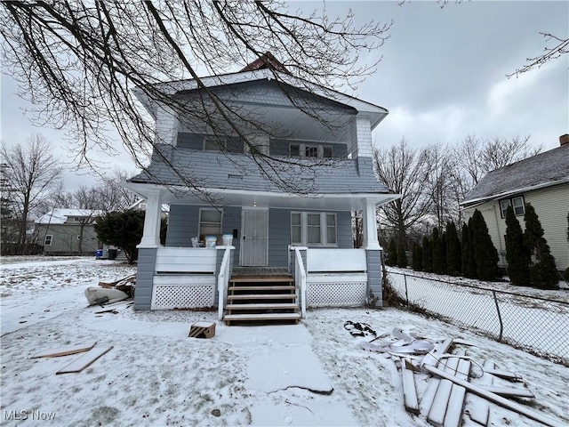 snow covered back of property with a porch