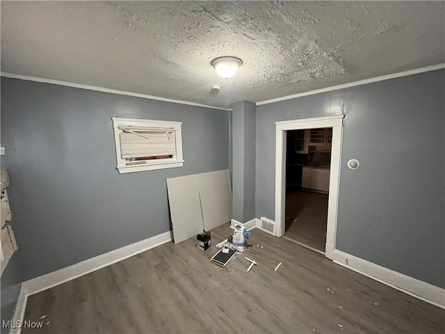 empty room featuring hardwood / wood-style flooring, ornamental molding, and a textured ceiling