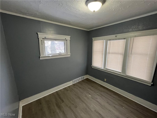 spare room with crown molding, dark hardwood / wood-style flooring, and a textured ceiling