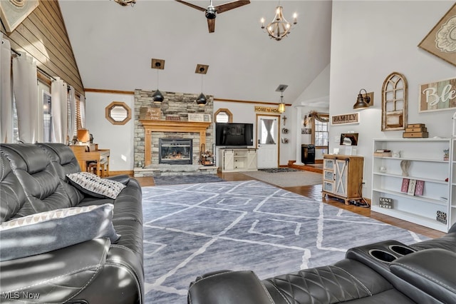 living room with wood-type flooring, a stone fireplace, crown molding, and high vaulted ceiling