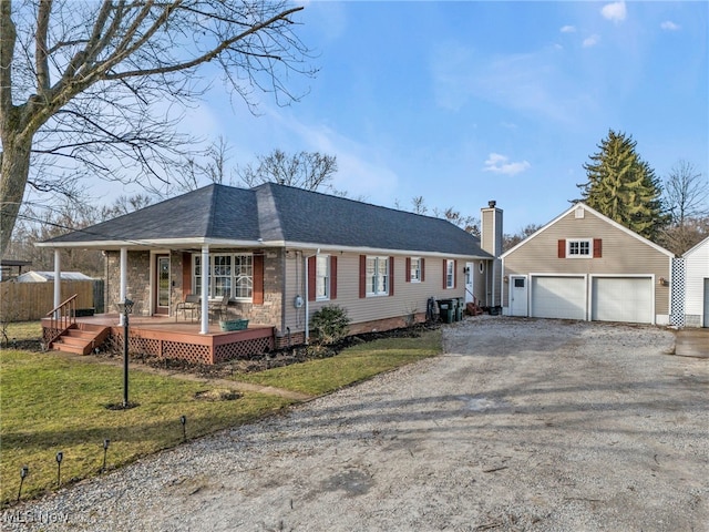 ranch-style home featuring a porch, a garage, an outdoor structure, and a front lawn