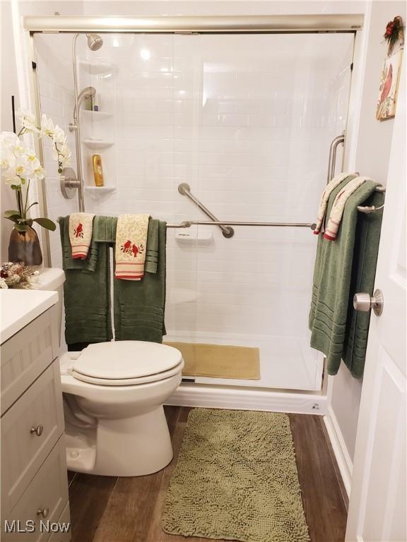 bathroom with a shower with door, toilet, hardwood / wood-style flooring, and vanity