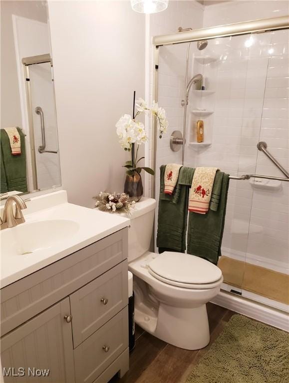 bathroom featuring vanity, toilet, a shower with shower door, and hardwood / wood-style floors