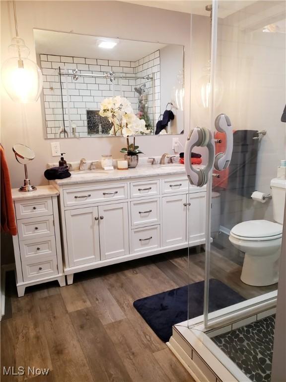 bathroom featuring hardwood / wood-style flooring, toilet, vanity, and walk in shower