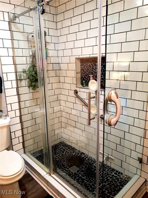 bathroom with hardwood / wood-style floors, toilet, and walk in shower