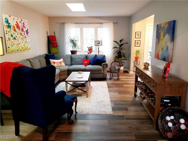 living room featuring dark wood-type flooring and a skylight