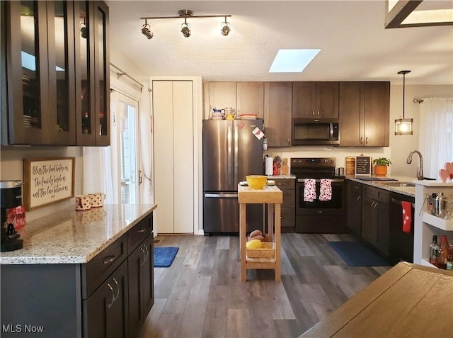 kitchen featuring dark hardwood / wood-style flooring, decorative light fixtures, dark brown cabinets, light stone counters, and appliances with stainless steel finishes