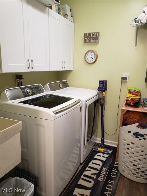 clothes washing area with dark hardwood / wood-style flooring, sink, separate washer and dryer, and cabinets