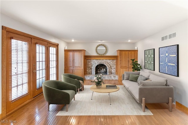 living room with a fireplace, light hardwood / wood-style floors, and a healthy amount of sunlight