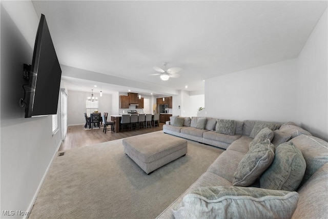 living room featuring wood-type flooring and ceiling fan with notable chandelier