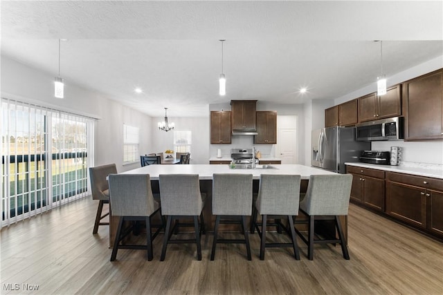 kitchen featuring appliances with stainless steel finishes, a breakfast bar, an island with sink, and dark brown cabinets