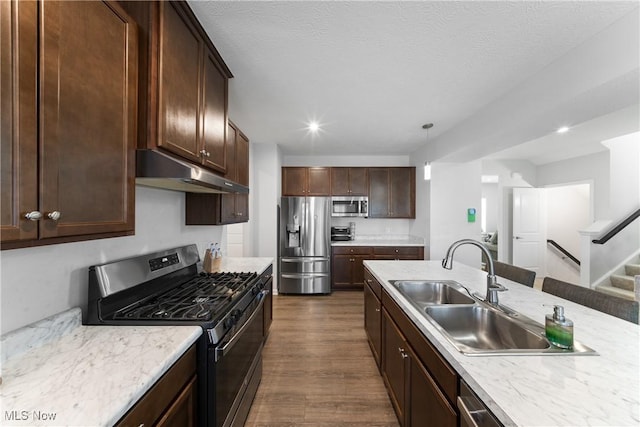 kitchen with sink, stainless steel appliances, dark hardwood / wood-style floors, dark brown cabinetry, and decorative light fixtures