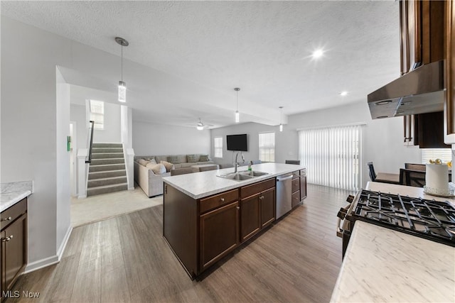 kitchen featuring dishwasher, an island with sink, sink, hanging light fixtures, and light hardwood / wood-style floors