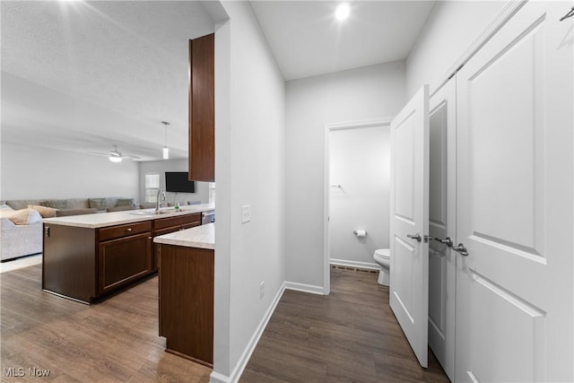 kitchen with ceiling fan, sink, dark hardwood / wood-style flooring, and kitchen peninsula