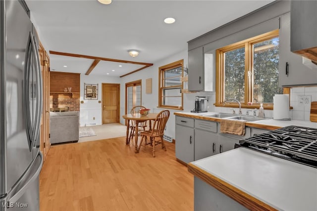 kitchen featuring sink, stainless steel fridge, gray cabinets, light hardwood / wood-style floors, and decorative backsplash