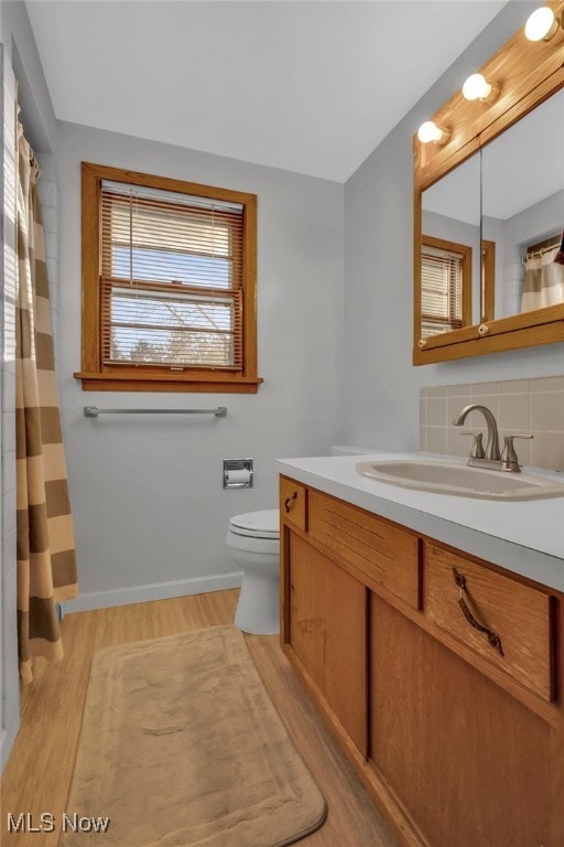 bathroom featuring tasteful backsplash, vanity, hardwood / wood-style flooring, and toilet