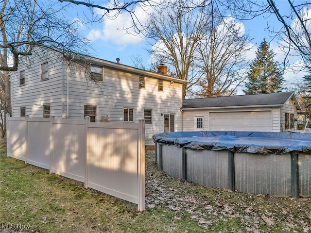 rear view of house featuring a garage and a covered pool