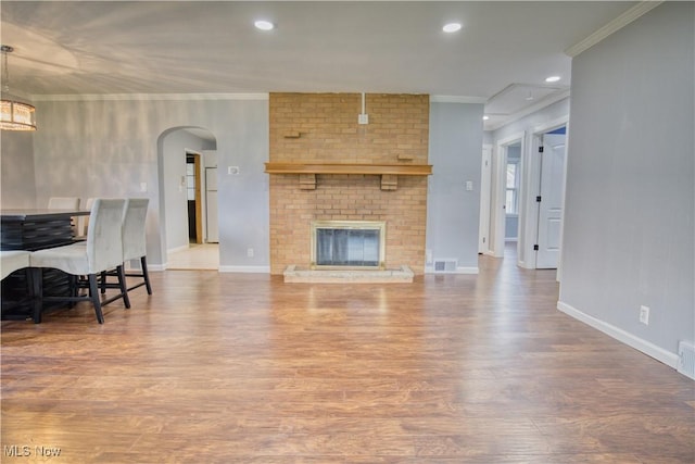 living room with wood-type flooring, a fireplace, and crown molding