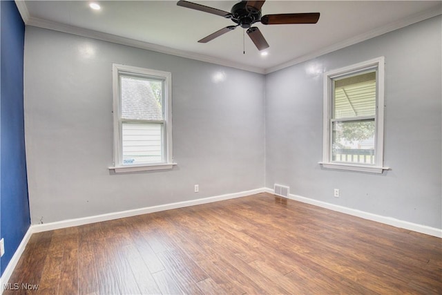 spare room with crown molding, a healthy amount of sunlight, and dark hardwood / wood-style flooring