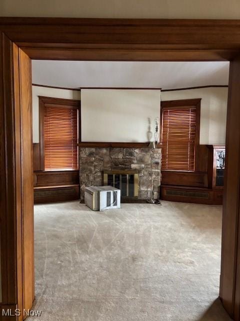 unfurnished living room with a stone fireplace and carpet