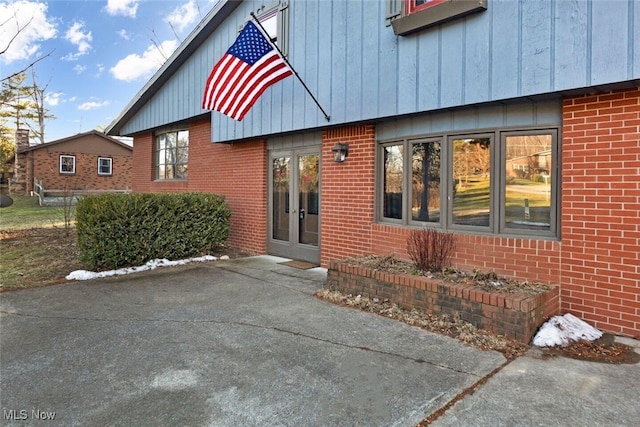 view of exterior entry with brick siding and french doors