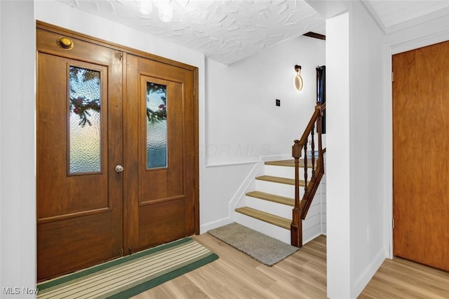 foyer with stairs, baseboards, and light wood-type flooring