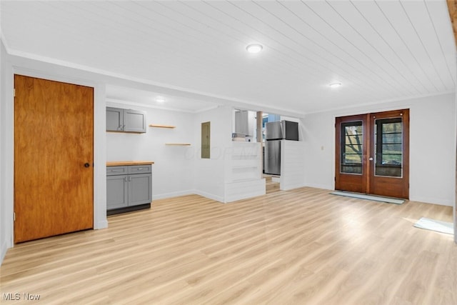 unfurnished living room with baseboards, electric panel, and french doors