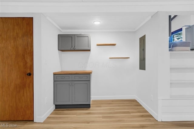 interior space with crown molding, baseboards, electric panel, and light wood finished floors