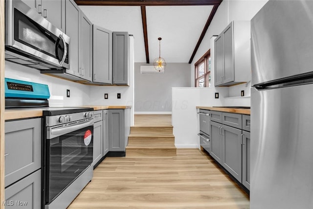kitchen featuring light wood-type flooring, butcher block countertops, gray cabinetry, and stainless steel appliances