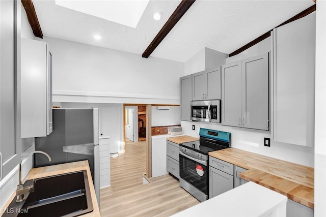 kitchen featuring gray cabinets, appliances with stainless steel finishes, butcher block counters, and light wood-type flooring