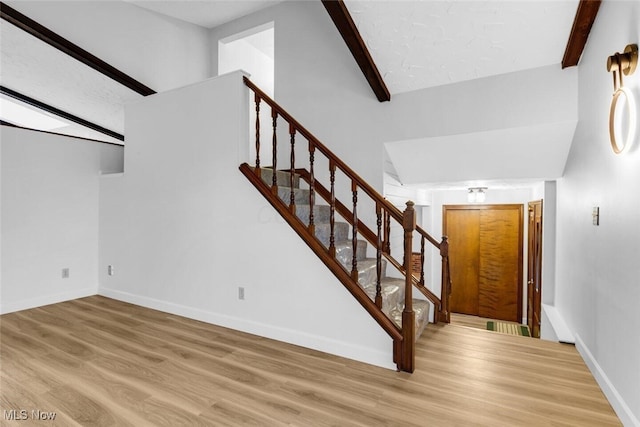 stairs with vaulted ceiling with beams, baseboards, and wood finished floors