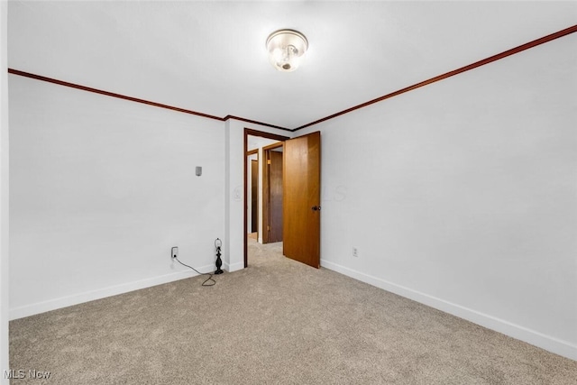 carpeted empty room with crown molding and baseboards