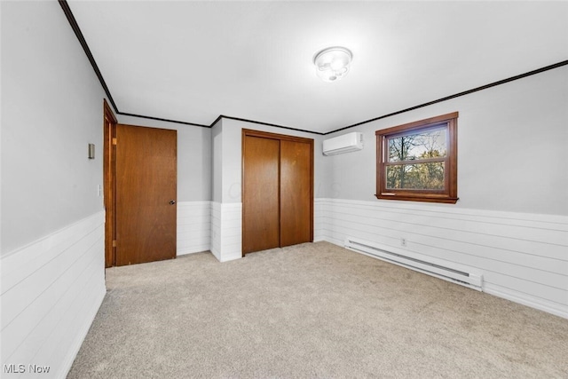 unfurnished bedroom featuring a closet, a baseboard radiator, a wall mounted AC, and a wainscoted wall