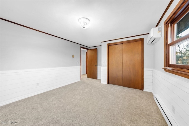 unfurnished bedroom with a baseboard heating unit, a wall mounted AC, carpet, and a wainscoted wall