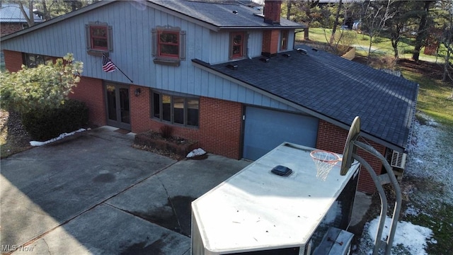 exterior space with brick siding, a shingled roof, a chimney, and outdoor dining space
