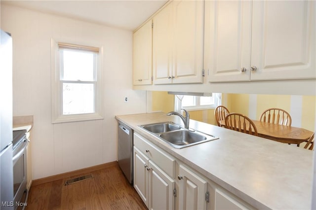 kitchen with appliances with stainless steel finishes, sink, hardwood / wood-style floors, and white cabinets