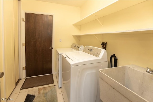 washroom featuring light tile patterned flooring, sink, and washer and clothes dryer