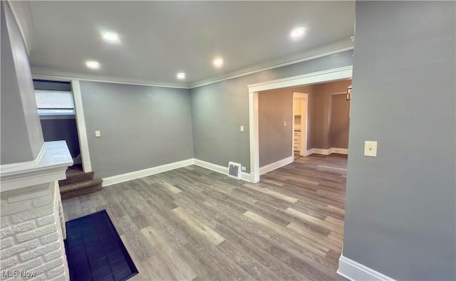 unfurnished living room with wood-type flooring and crown molding