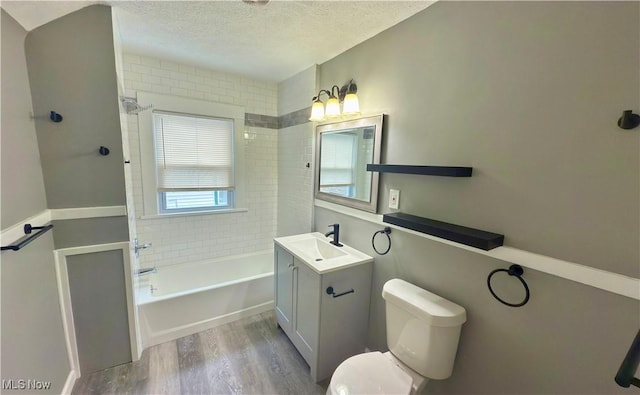 full bathroom with toilet, tiled shower / bath, wood-type flooring, a textured ceiling, and vanity