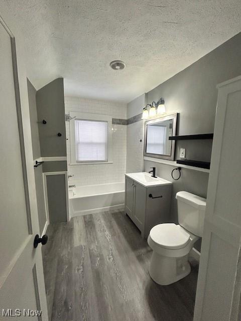 bathroom with vanity, toilet, hardwood / wood-style floors, and a textured ceiling