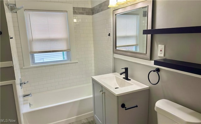 full bathroom with vanity, tiled shower / bath, and toilet