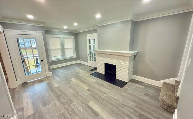 unfurnished living room with a brick fireplace, wood-type flooring, and ornamental molding